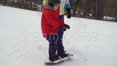 年轻人<strong>滑雪板</strong>教练教小男孩如何骑<strong>滑雪板</strong>。 冬季活动概念
